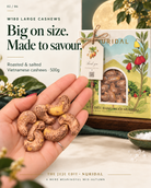 Large W180 skin-on cashews held in a hand beside the NURIDAL 500g gift box.